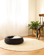 Charcoal merino wool cat bed by Solace Aura in a natural living room setting, handmade from 100% wool with a soft, sculptural form designed for modern homes.