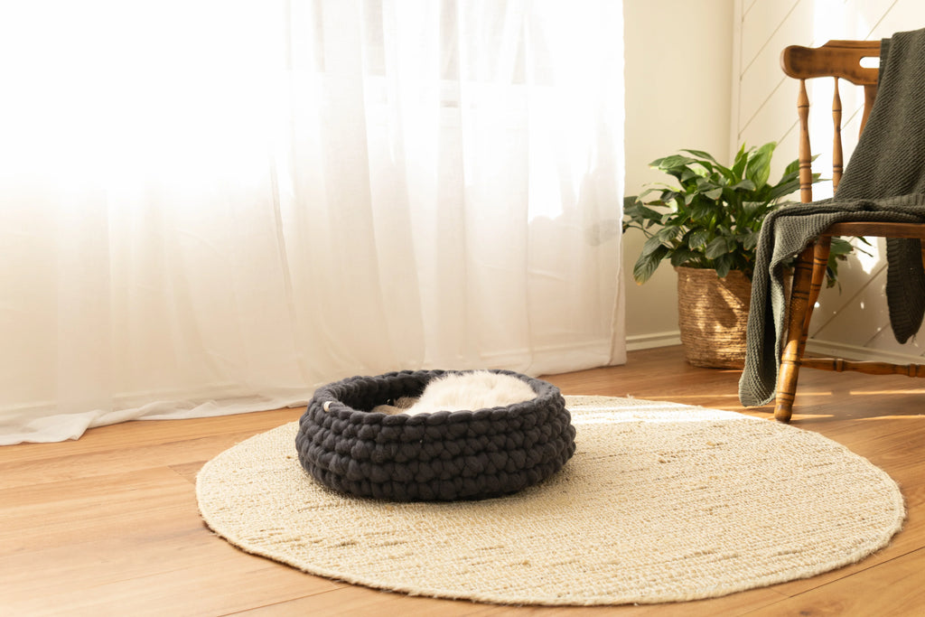 Charcoal merino wool cat bed by Solace Aura in a natural living room setting, handmade from 100% wool with a soft, sculptural form designed for modern homes.
